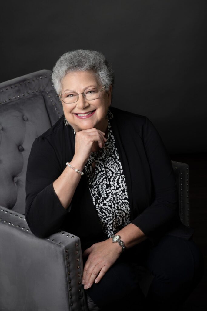 Toni Gitles smiling sitting in chair