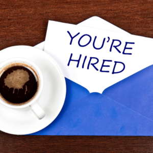 You're Hired written on napkin next to coffee cup