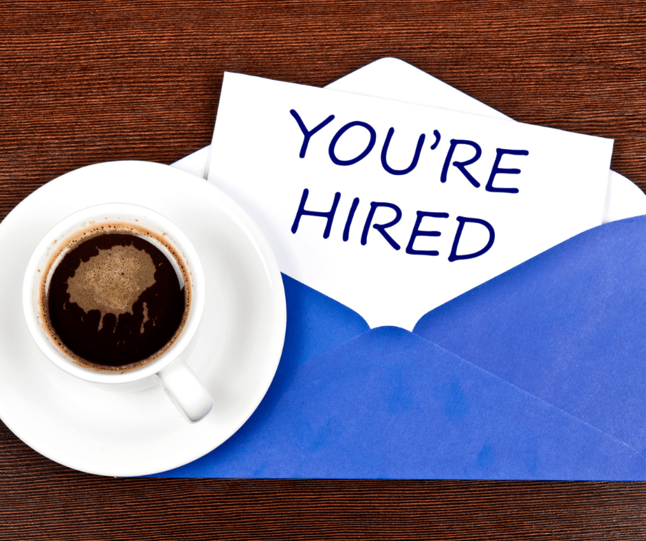 You're Hired written on napkin next to coffee cup